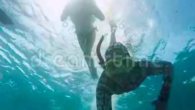 几个穿泳装和脚蹼的游客在巴厘岛附近的海洋里潜水。 年轻女子正在附近潜水